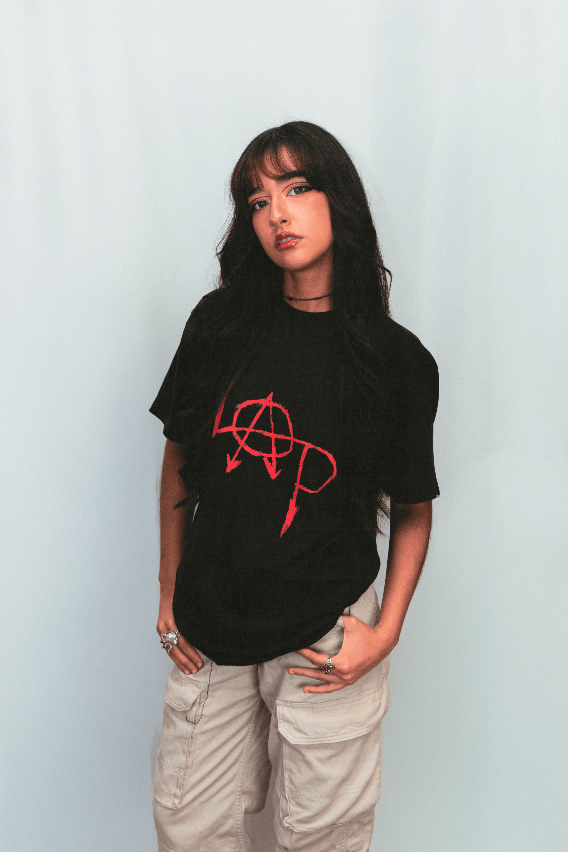 Person wearing a black t-shirt with a red logo against a light background