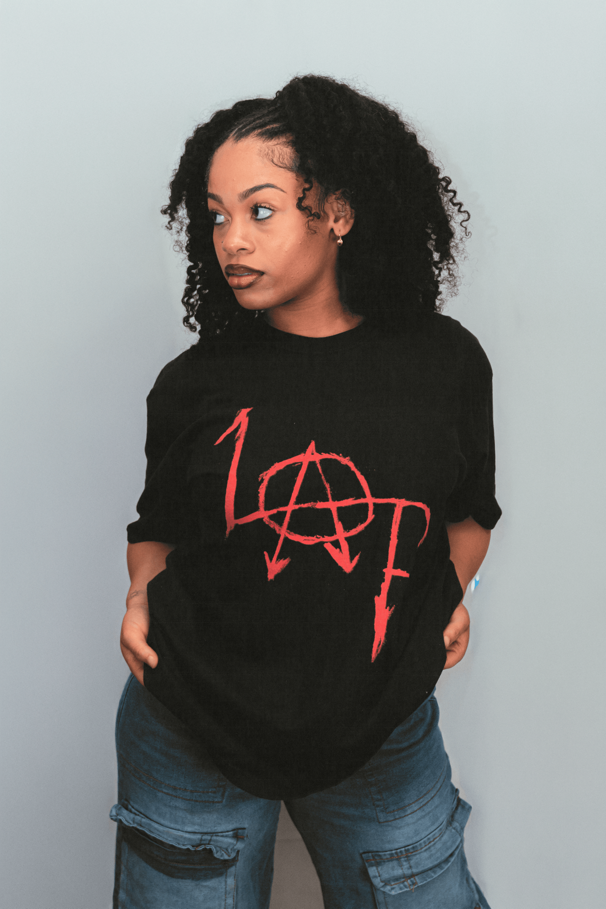 Person wearing a black t-shirt with red logo against a plain background