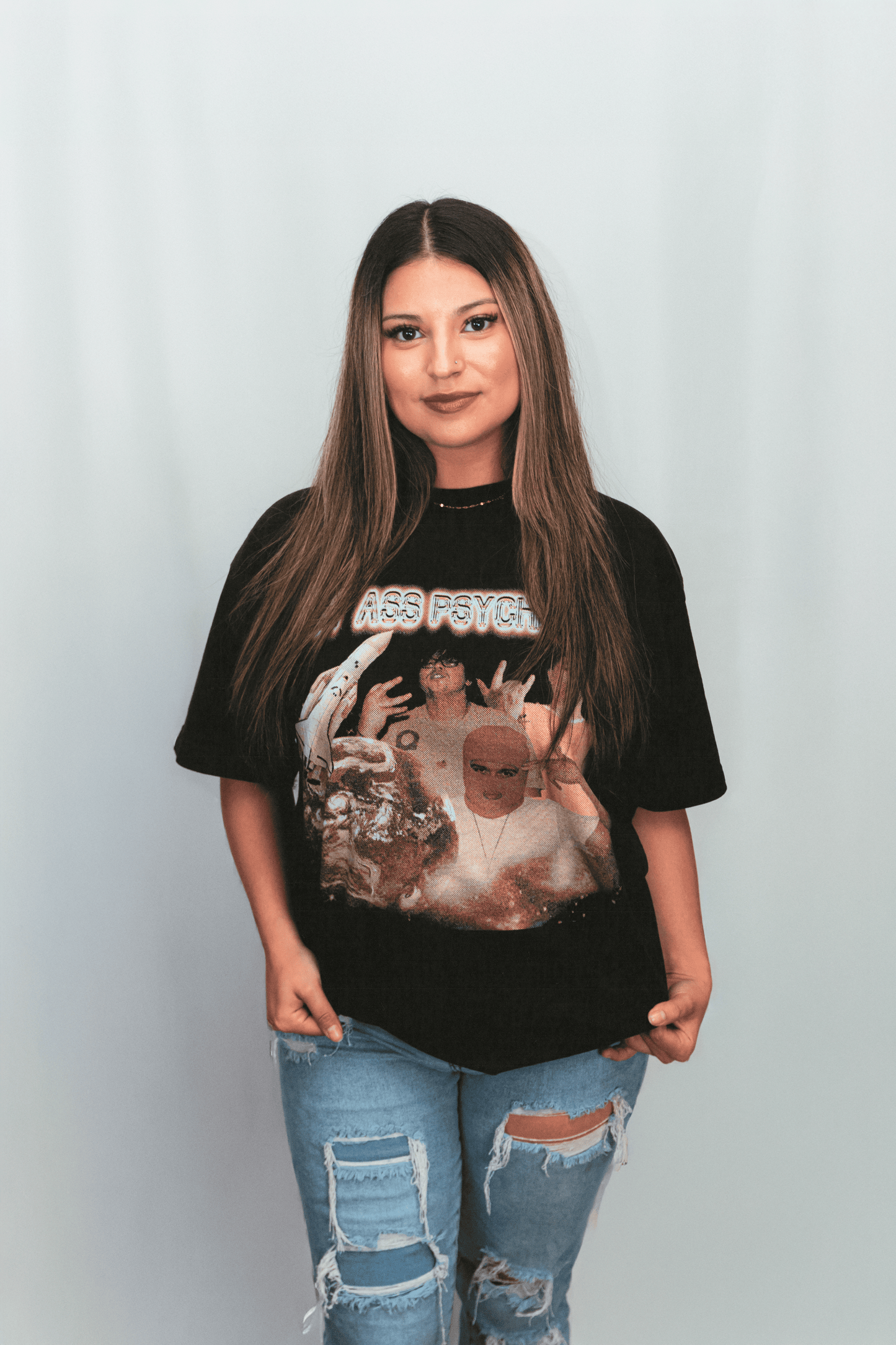 Person wearing a black graphic t-shirt with a design on a plain background