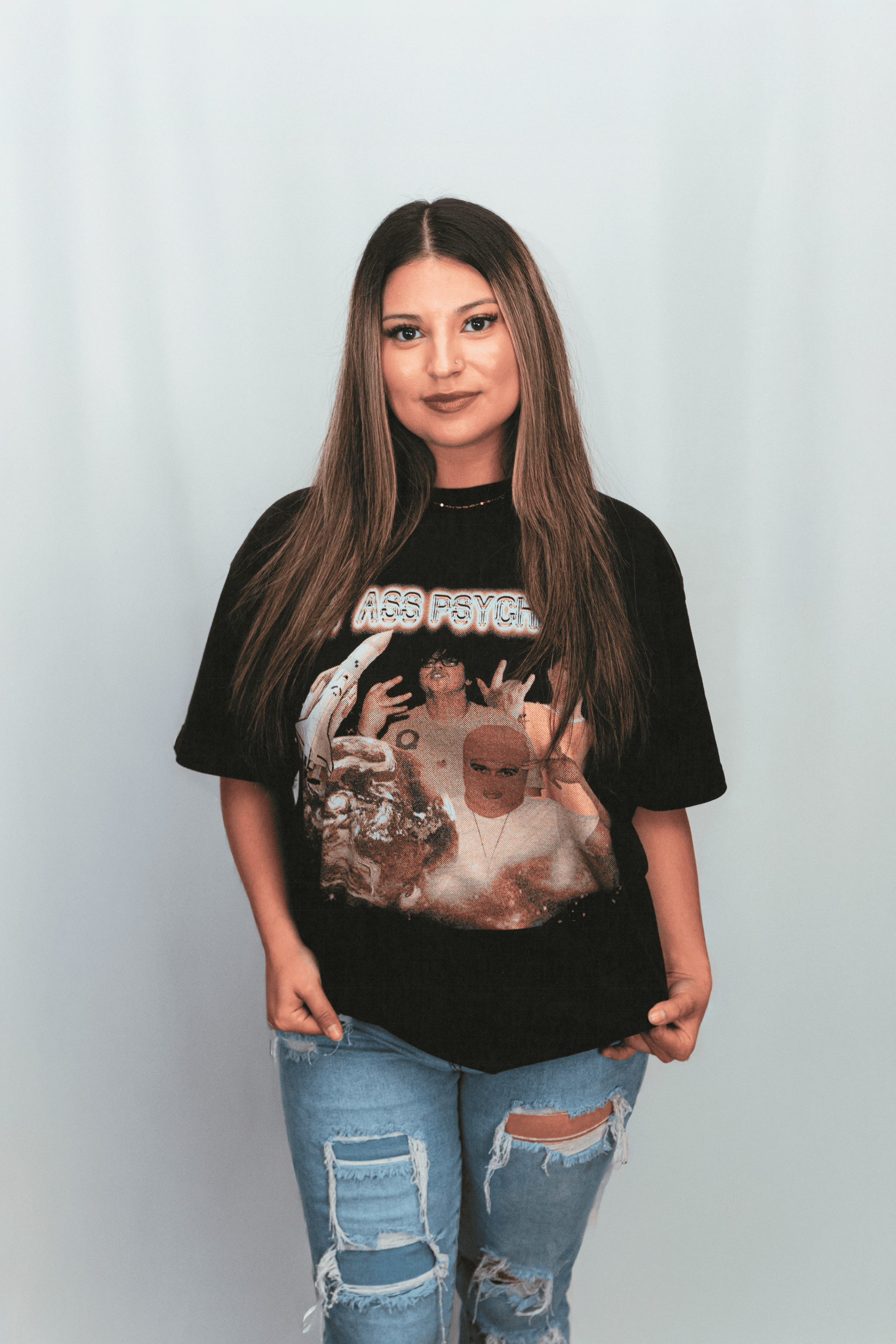 Person wearing a black graphic t-shirt with a design on a plain background